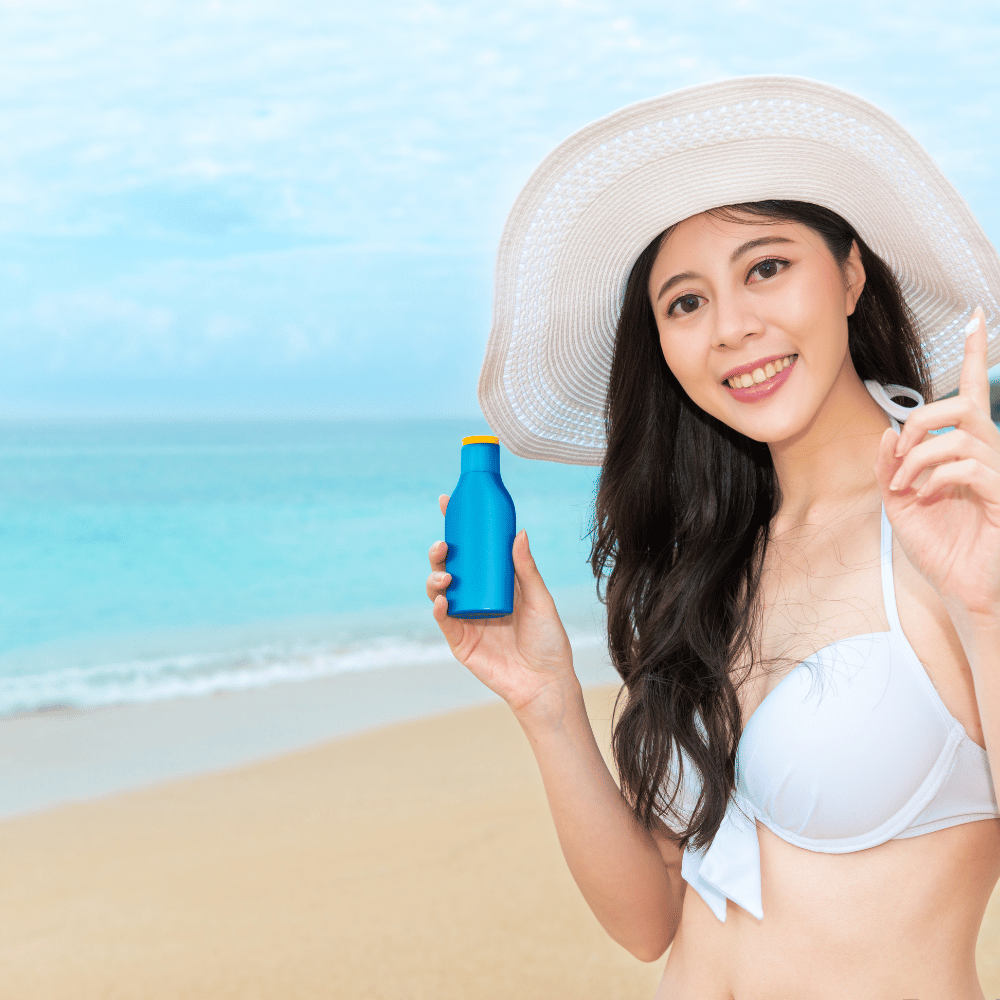 korean girl holding bottle of sunscreen standing on the beach