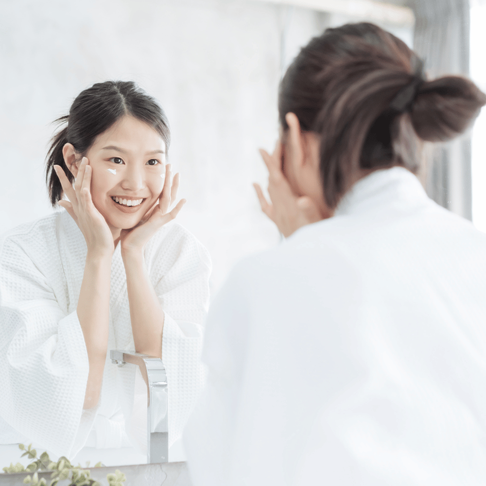 Korean woman moisturizing her face in a mirror