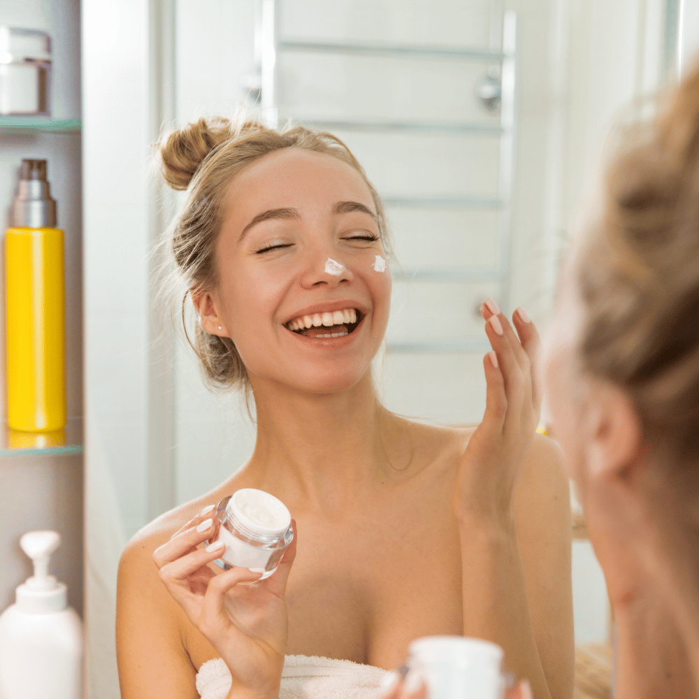laughing teenager applying moisturizer in a mirror