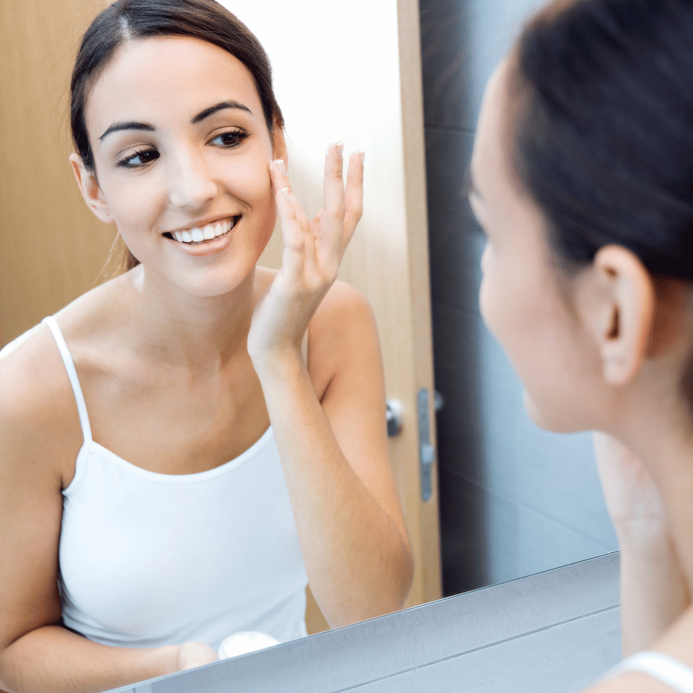 teenager applying moisturizer in mirror