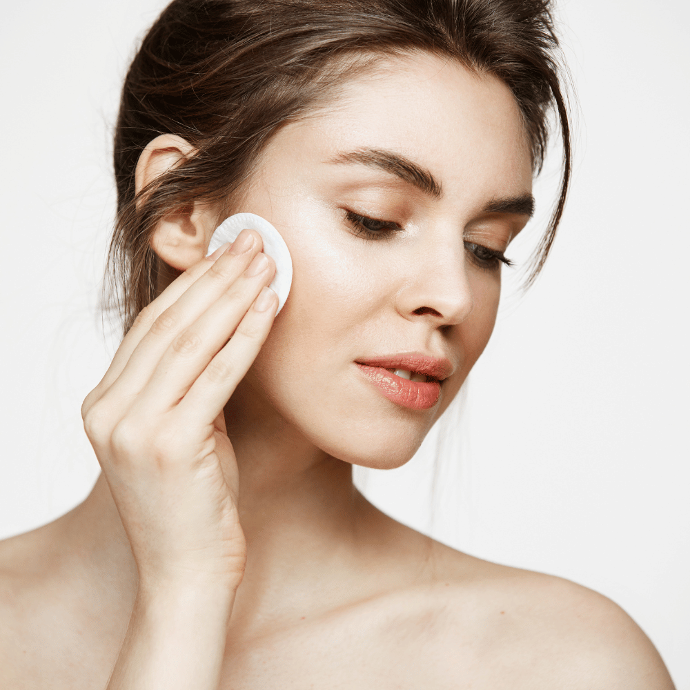 woman applying toner to her face with cotton pad