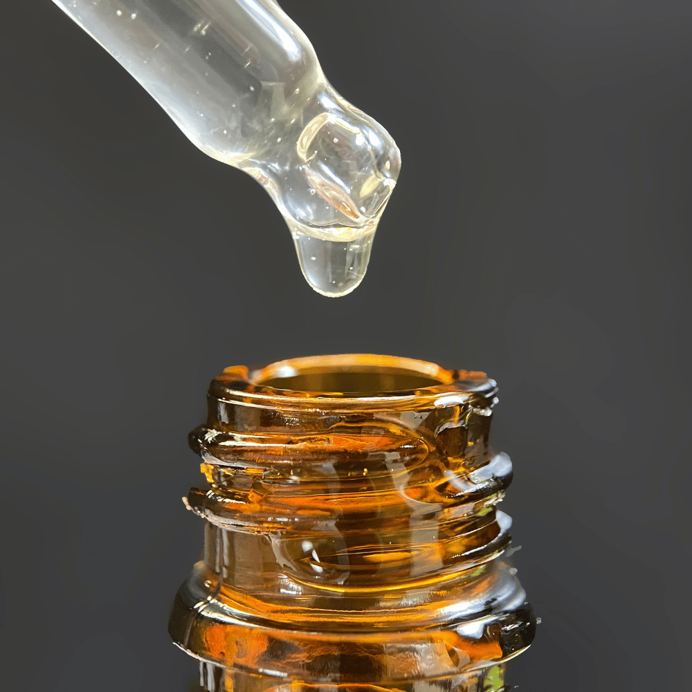closeup of the top of serum bottle with dropper dripping into bottle