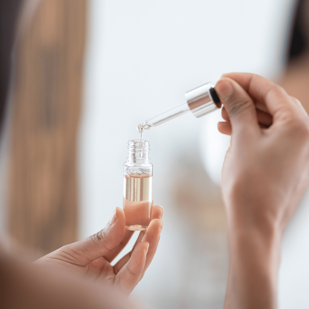closeup of a bottle of serum with a dropper in a woman's hand