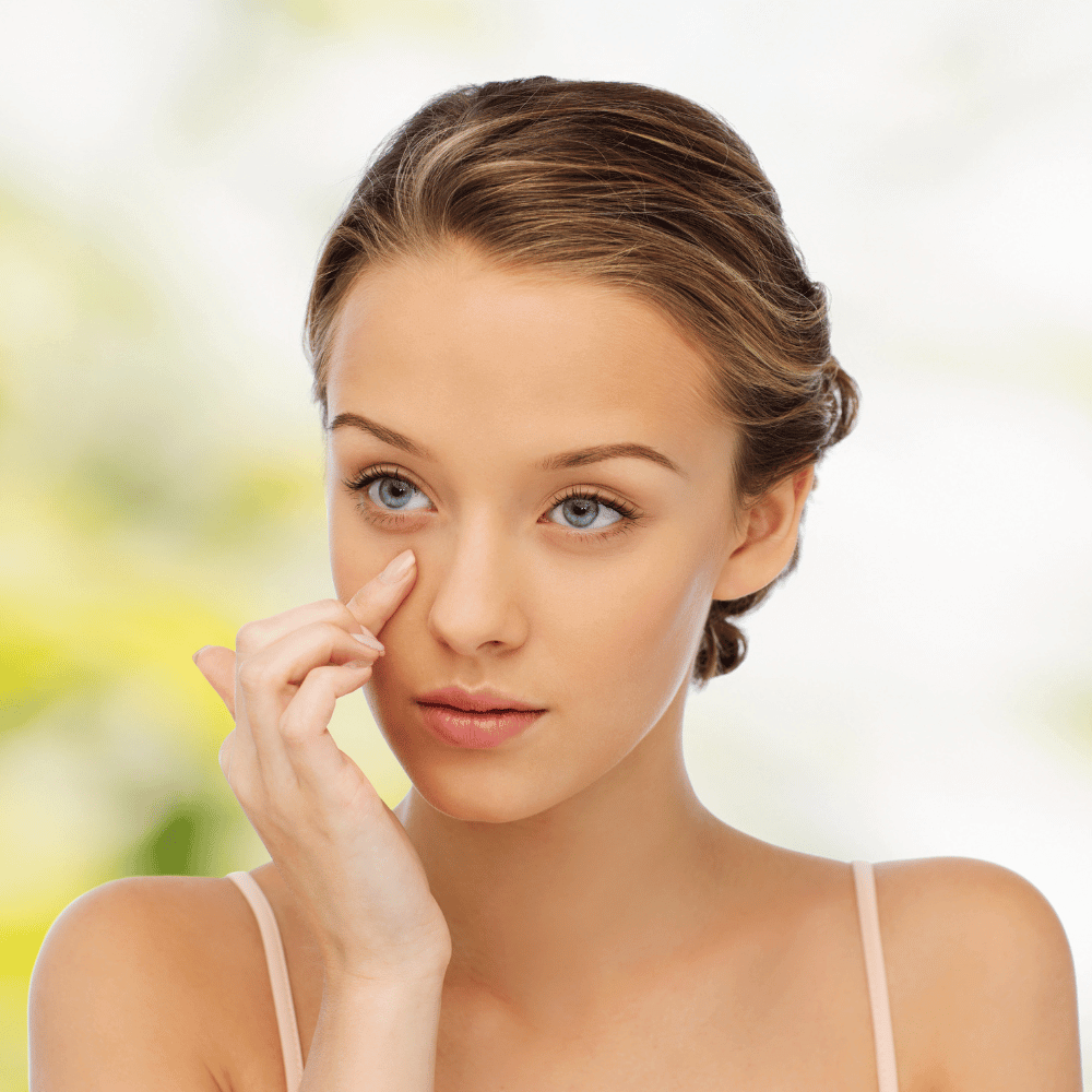 young woman with her finger placed under her eye