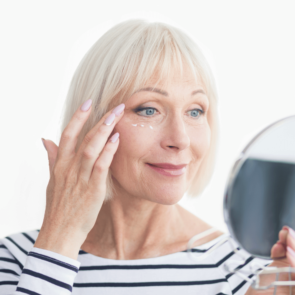 close up of older woman putting dots of eye cream under her eyes
