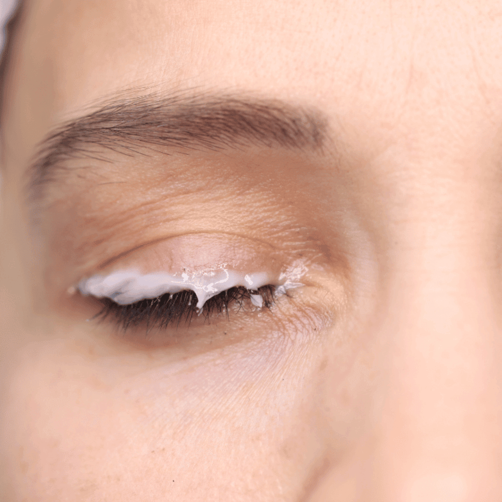 closeup of a woman's eyelid with eye cream sitting along the upper lid lash line
