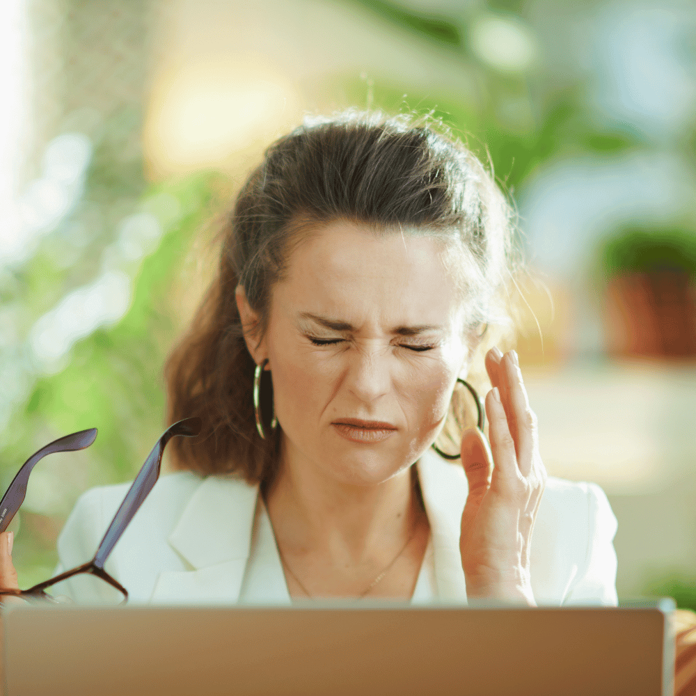 woman squinting her eyes tight after removing her eye glasses