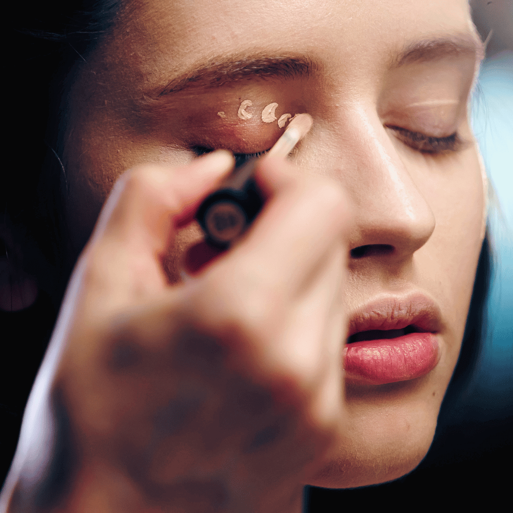 woman putting concealer on her eyelid.