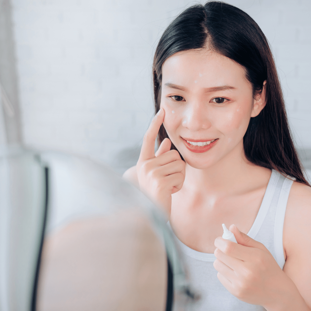 woman applying eye cream in front of her mirror
