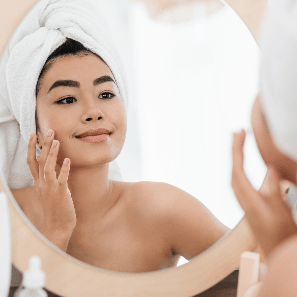 woman looking at her skin in the mirror